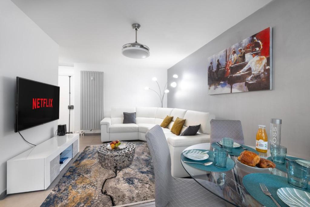 un salon avec un canapé blanc et une télévision dans l'établissement Suite Ioana - Appartement à Cannes, à Cannes