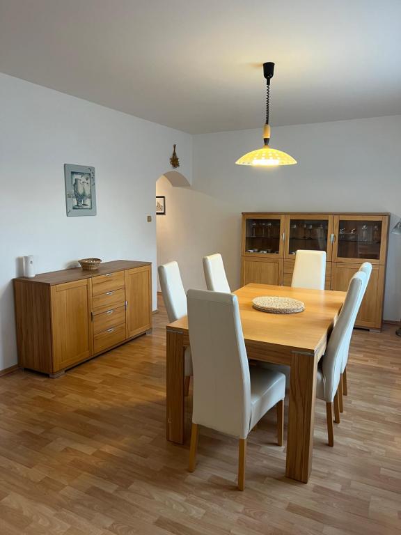 ZloniceApartmán s venkovním bazénem Zlonice的一间带木桌和白色椅子的用餐室