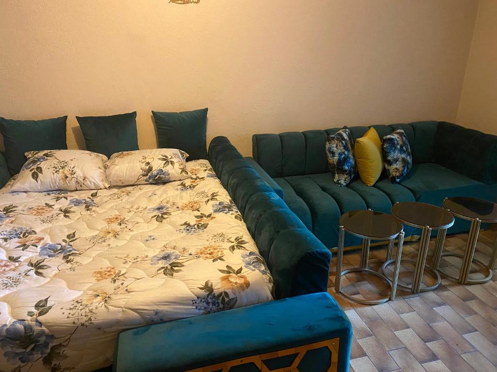 - un canapé bleu dans un salon avec deux tabourets dans l'établissement Rahou, à Étampes