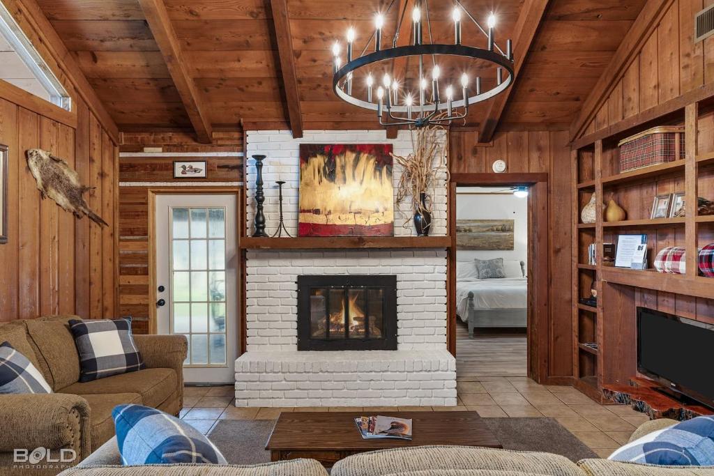 a living room with a fireplace and a chandelier at Canoes, Firepit, Outdoor Dining, Cedar Lodge in Karnack
