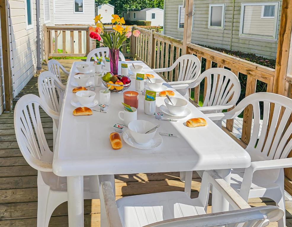 a white table with plates of food on a deck at Le Cotin Normand in Litteau