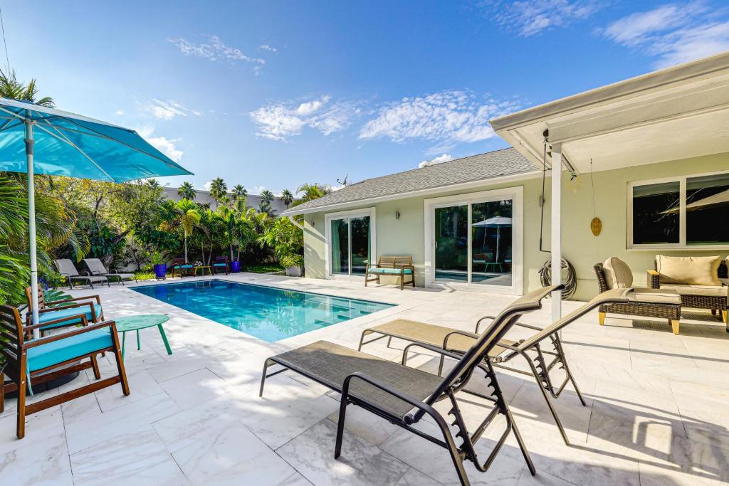a house with a pool and a patio with chairs and an umbrella at 2 Mi to Deerfield Beach Home with Outdoor Oasis! in Deerfield Beach