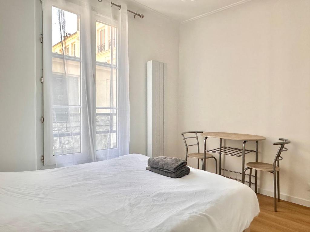 une chambre avec un lit, une table et des chaises dans l'établissement Comfortable studio Notre-Dame de Lorette Rodier, à Paris