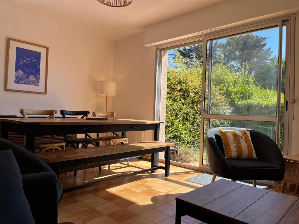 un salon avec une table et une grande fenêtre dans l'établissement La maison des dunes de Kerambigorn, à Fouesnant