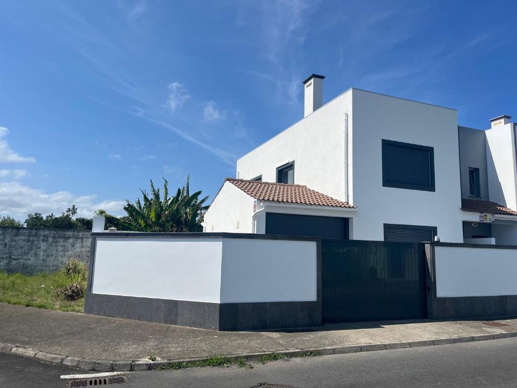 a white house with blank billboards in front of a street at Casa Senhora Da Estrela 1, 2 or 3 bedrooms in Ribeira Grande