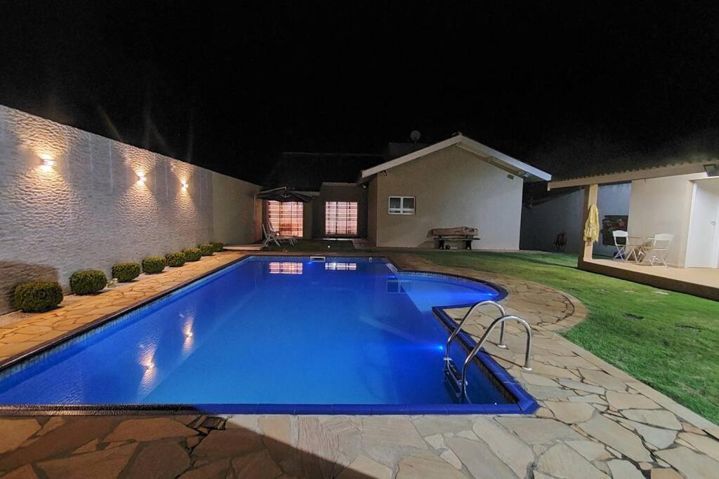 a large blue swimming pool in a yard at night at Fuja de tudo que está consumindo sua paz! in Atibaia