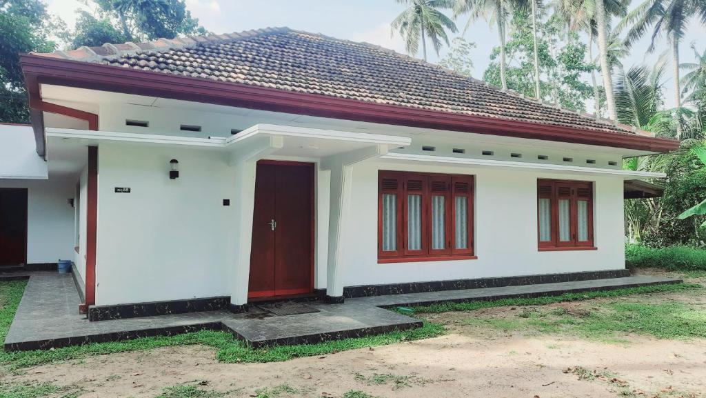 a small white house with a red door at Rustic Villa 7 in Weligama