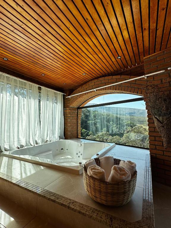 a large bathroom with a tub and a large window at Pousada Quinta do Barao in Conceição da Ibitipoca