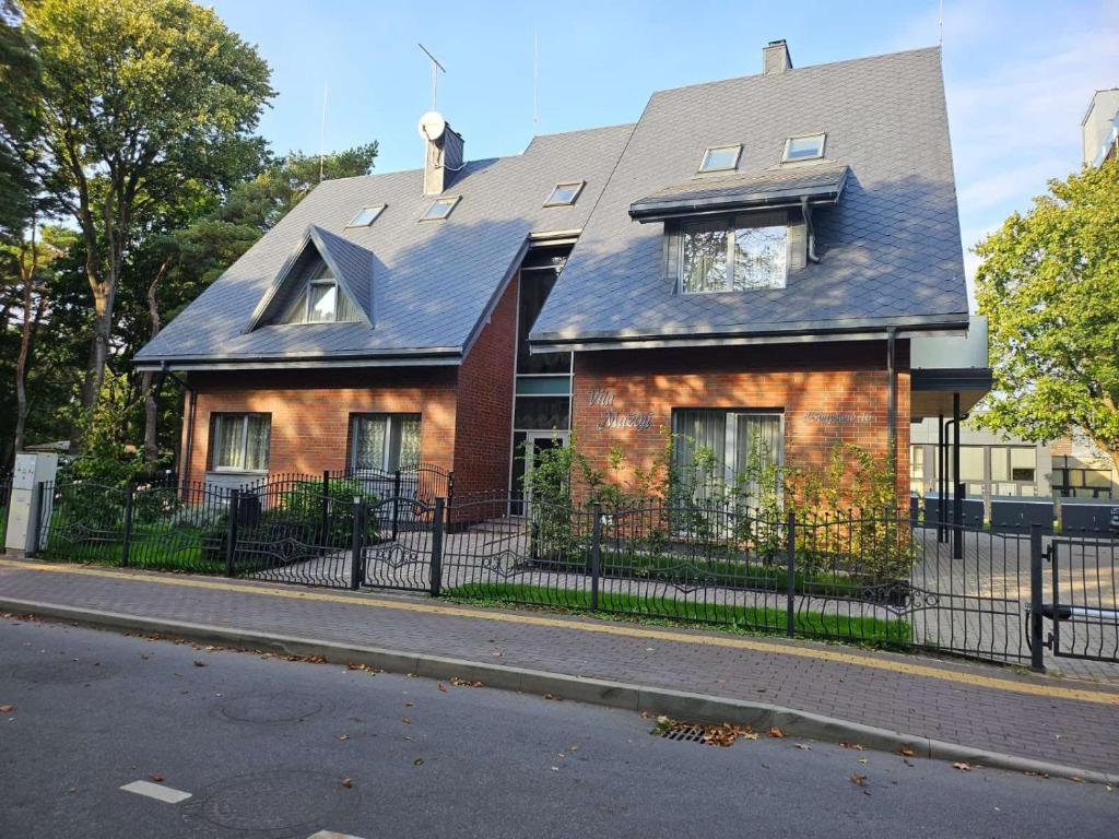 a brown brick house with a black fence at Vila Mažoji apartamentai in Palanga
