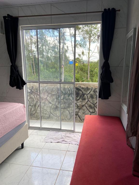 a bedroom with a large window with a red carpet at Kitnet Europa in Bonito