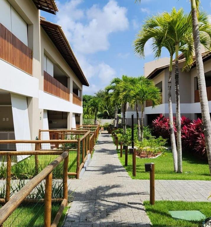 a walkway in front of a building with palm trees at Village Térreo Acqua Guarajuba in Guarajuba