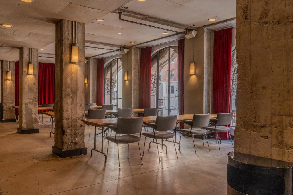 a dining room with tables and chairs and red curtains at STILE Downtown Los Angeles by Kasa in Los Angeles