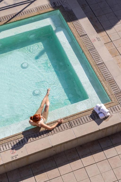 a woman laying in a swimming pool at STILE Downtown Los Angeles by Kasa in Los Angeles
