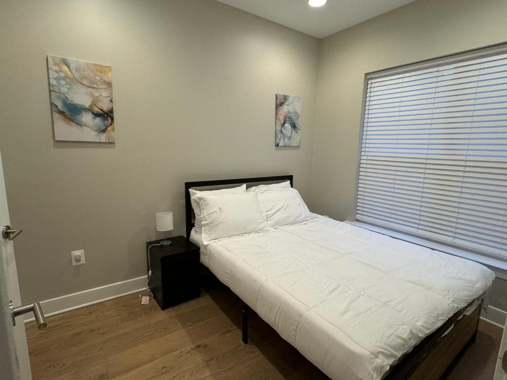 a bedroom with a bed with white sheets and a window at LUX Entire House 4BR in DC - Private Garage in Washington