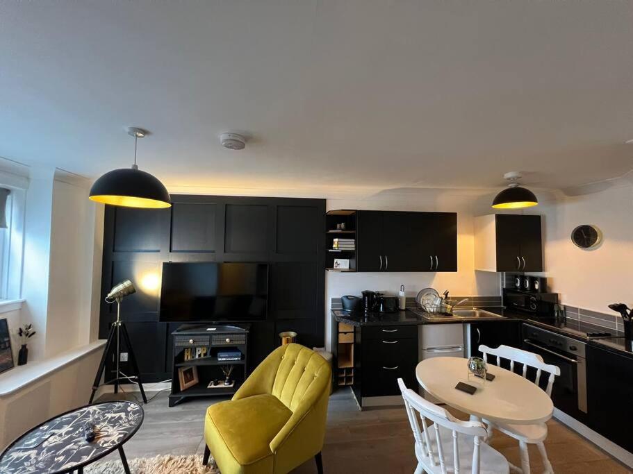 a living room with a table and a yellow chair at Elro House Holiday Let in Tillicoultry