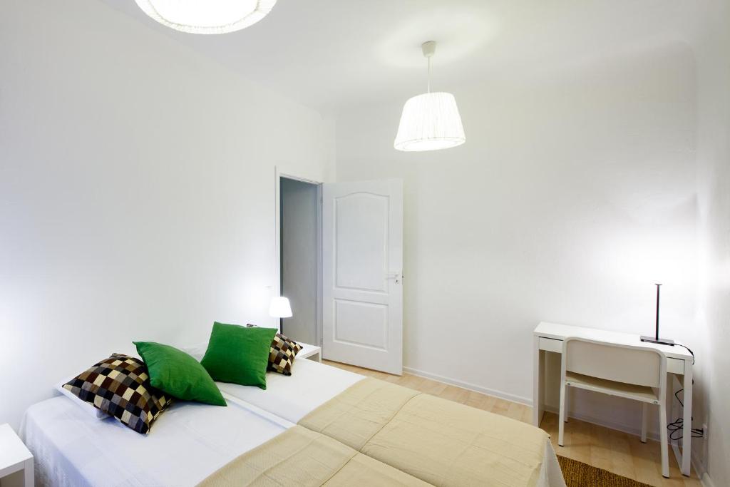 a white bedroom with a bed and a desk at Lote Apartment in Rīga