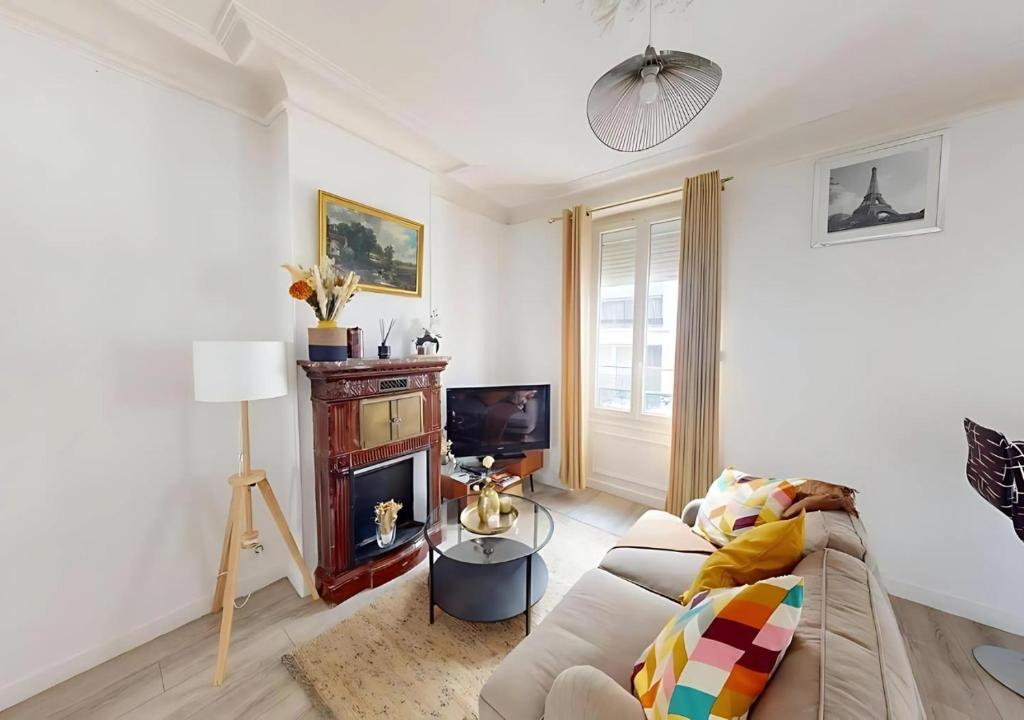 Una sala de estar con un sofá y una chimenea. en Cozy APT in Le Perreux with Parisian Charm & Disneyland Fun, en Le Perreux-Sur-Marne