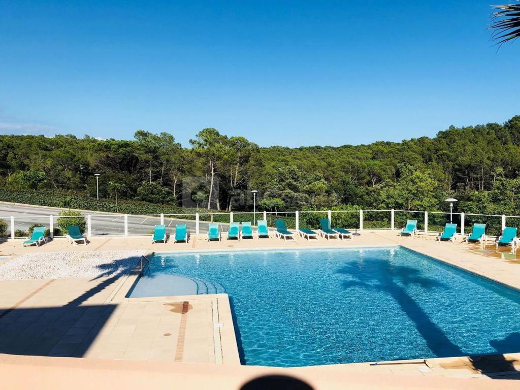 - une piscine avec des chaises bleues dans l'établissement Fabuleux appartement avec piscine, à Roquebrune-sur Argens