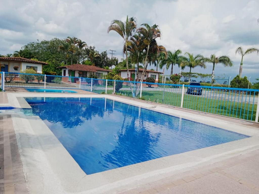 a large swimming pool with a fence and palm trees at Hotel campestre manantial del Quindio in Montenegro