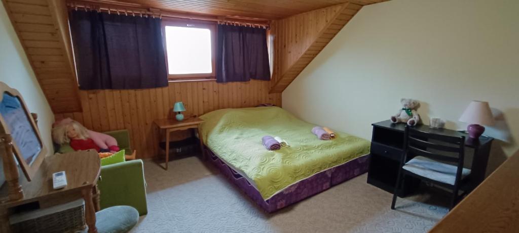 une petite chambre avec un lit et un enfant assis sur une chaise dans l'établissement Rigó Nyaralóház, à Lakitelek