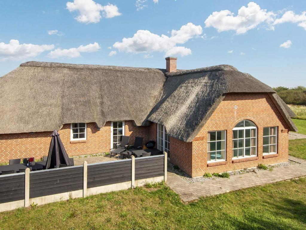 a brick house with a thatched roof on a field at Luxury Retreat with Pool in Ulfborg