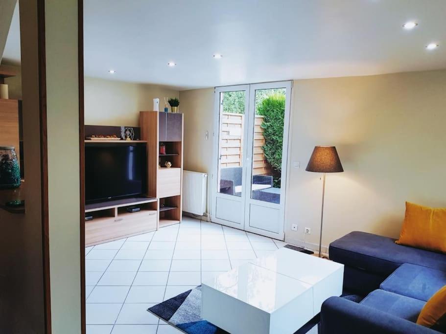 un salon avec un canapé bleu et une télévision dans l'établissement Charmant Pavillon - 15 min de Paris - Gare à 300 m, à Cormeilles-en-Parisis