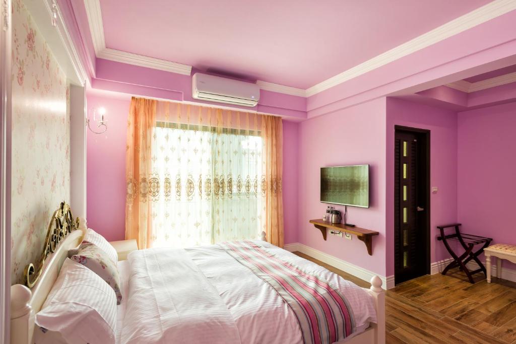 a purple bedroom with a bed and a window at Ediman Bed &amp; Breakfast in Hualien City