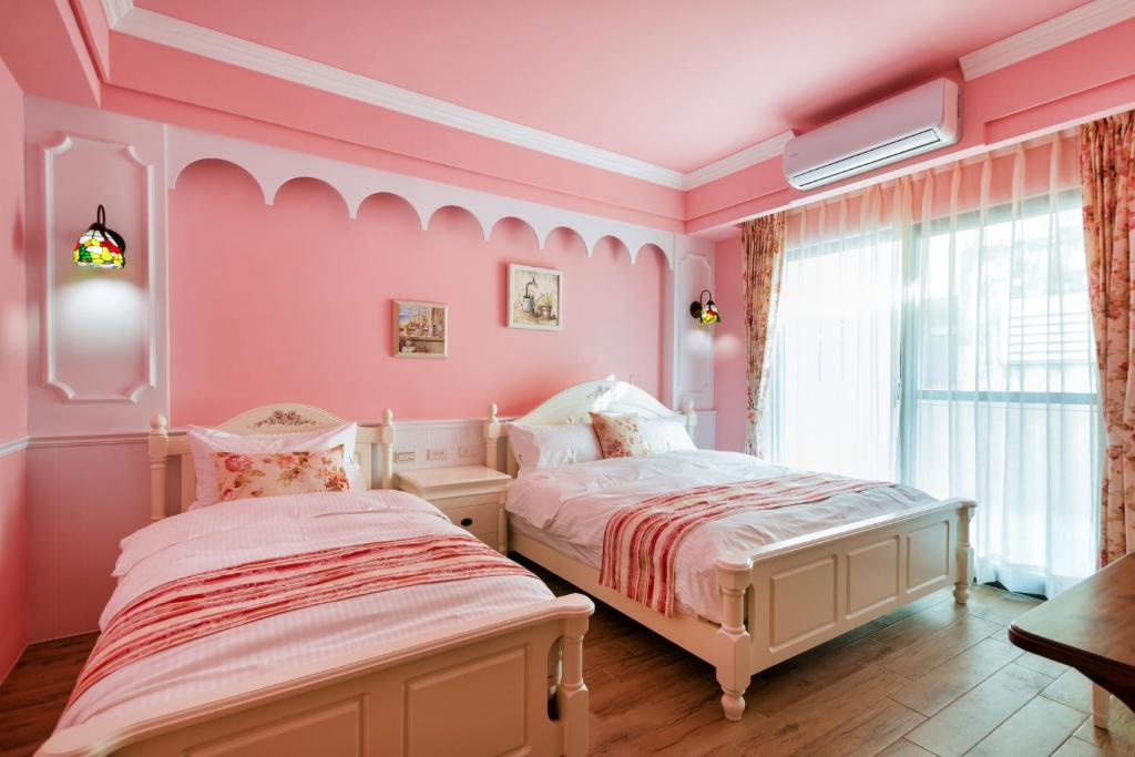 two beds in a bedroom with pink walls and a window at Ediman Bed & Breakfast in Hualien City
