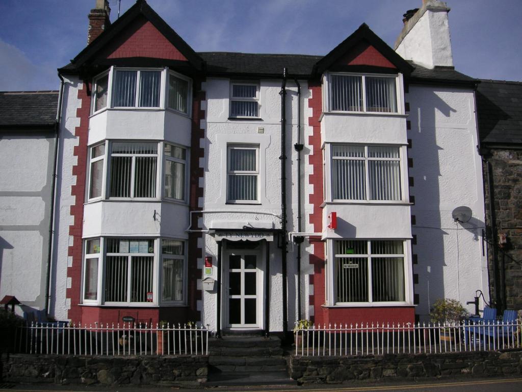 a white and red house with a fence at Ty Newydd Guest House in Trefriw