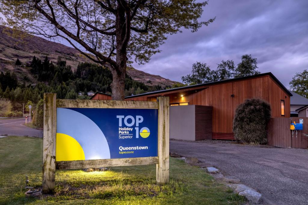a sign in the grass in front of a building at Queenstown Top 10 Holiday Park in Queenstown