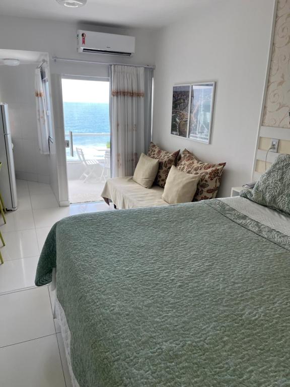 a bedroom with a bed and a couch and the ocean at Bahia Flat ap 206 in Salvador