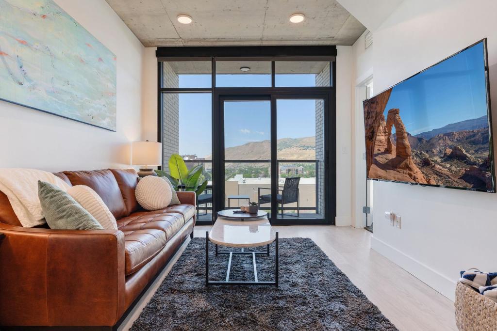 a living room with a brown couch and a large window at Impeccable1B Salt Palace & Delta - PoolSpaGymPrkgViews in American Towers Condominium