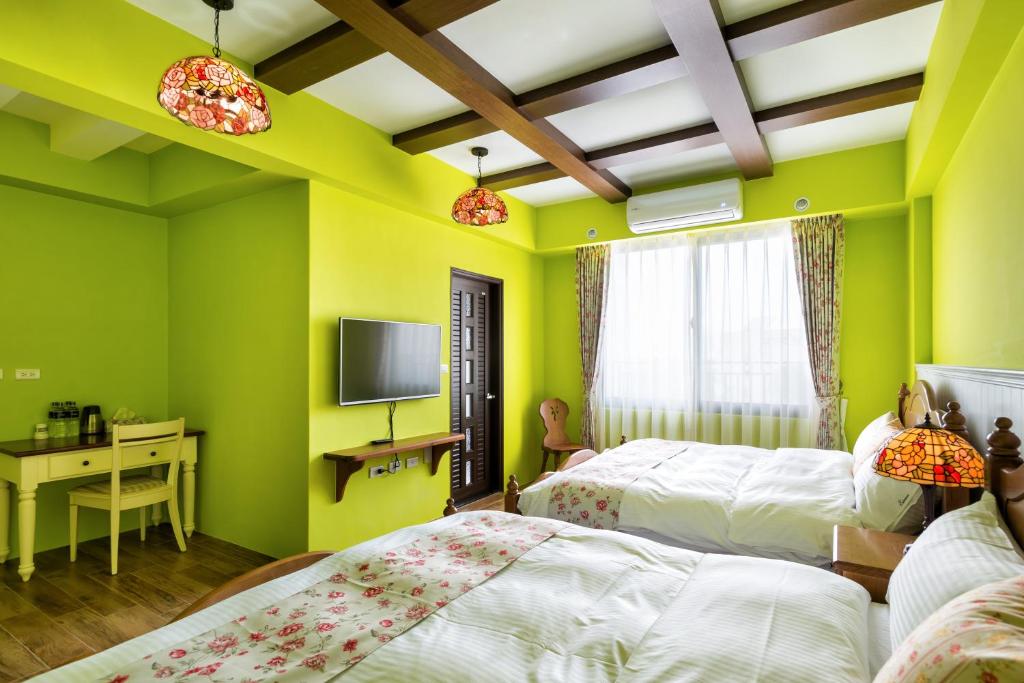 a green bedroom with two beds and a desk at Ediman Bed &amp; Breakfast in Hualien City