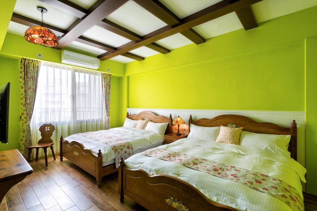 a green bedroom with two beds and a window at Ediman Bed &amp; Breakfast in Hualien City