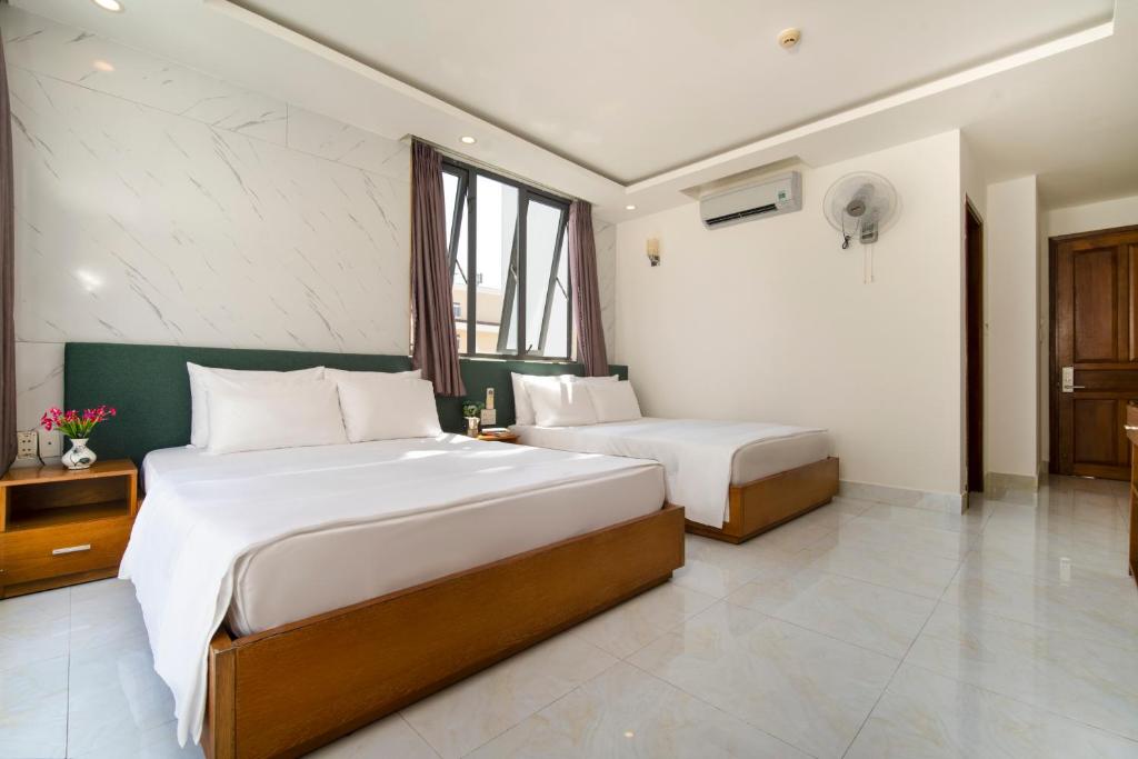 a hotel room with two beds and a window at Trang Ngan Hotel by THG in Danang