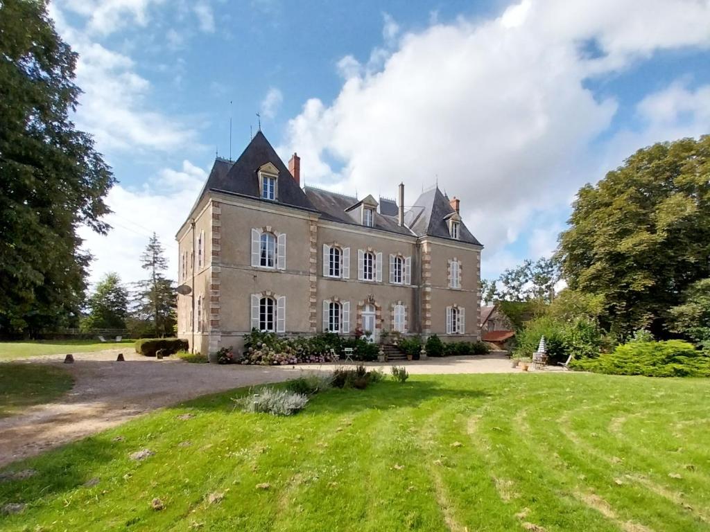 an old castle with a grassy field in front of it at Le manoir d'Estiveaux in Le Châtelet