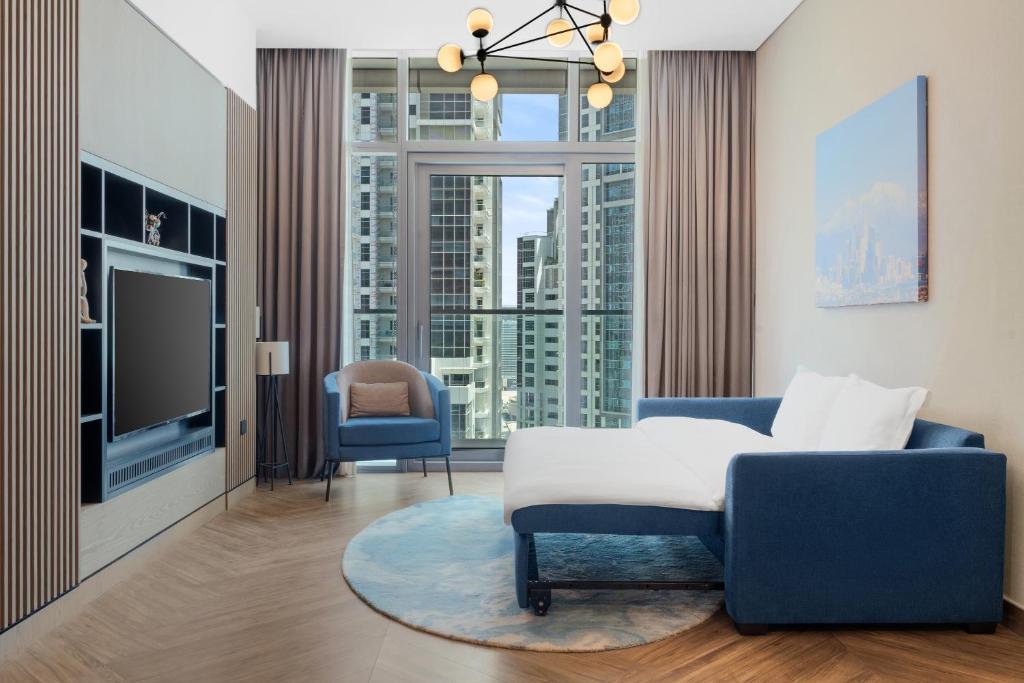a living room with a blue chair and a tv at Paramount Hotel Midtown in Dubai