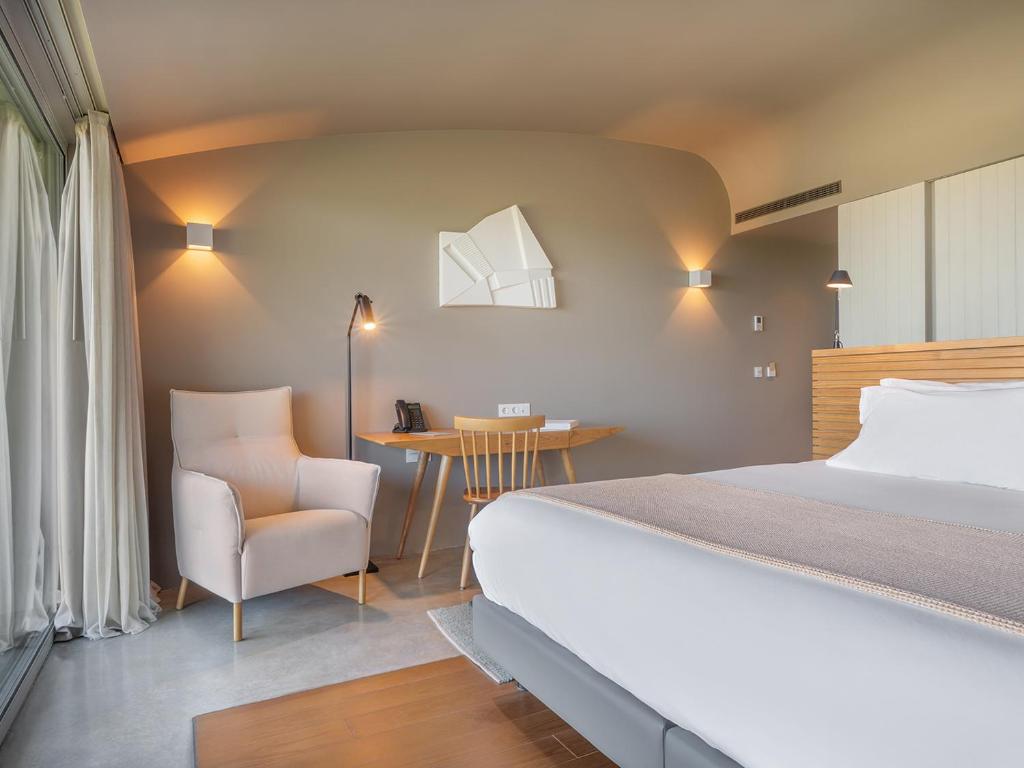 a bedroom with a bed and a chair and a table at Immerso Hotel, a Member of Design Hotels in Ericeira