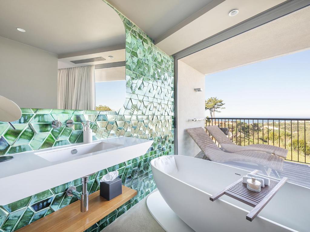 a bathroom with a tub and a sink and a balcony at Immerso Hotel, a Member of Design Hotels in Ericeira