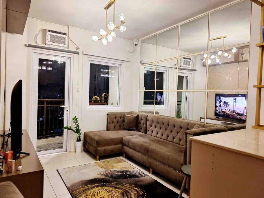 a living room with a brown couch and windows at 2-Bedroom Condo with Swimming Pool in Manila