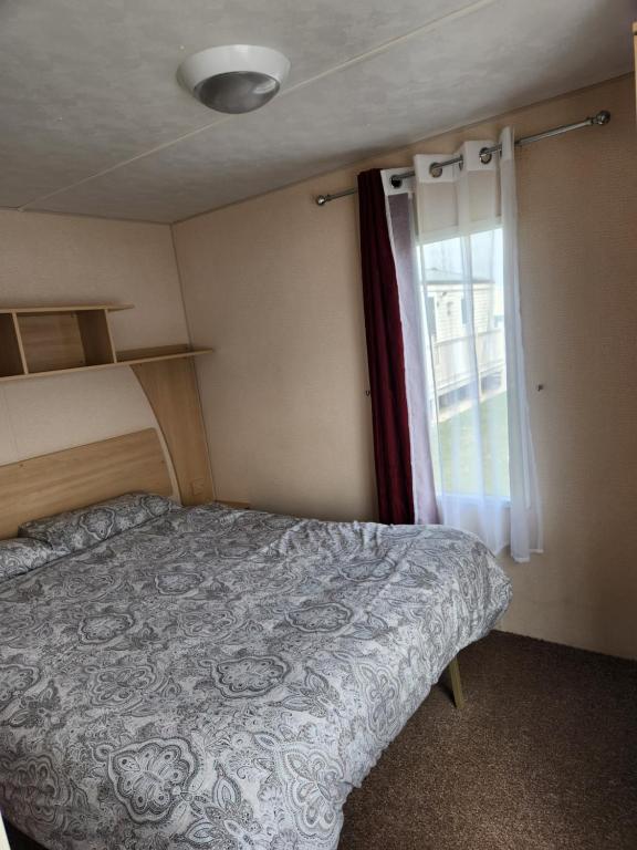a bedroom with a bed and a window at Ingoldmells, The Grange Holiday Park 3-Bedroom Caravan in Skegness