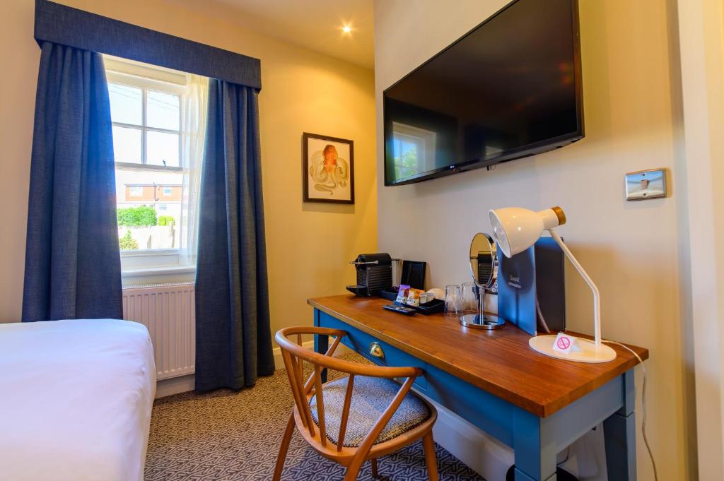 a hotel room with a desk with a bed and a television at Downs Hotel in Stanmer
