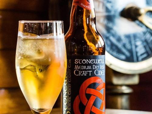 una bottiglia di birra seduta accanto a un bicchiere di The Beach, Days Bar and B&B a Inishbofin