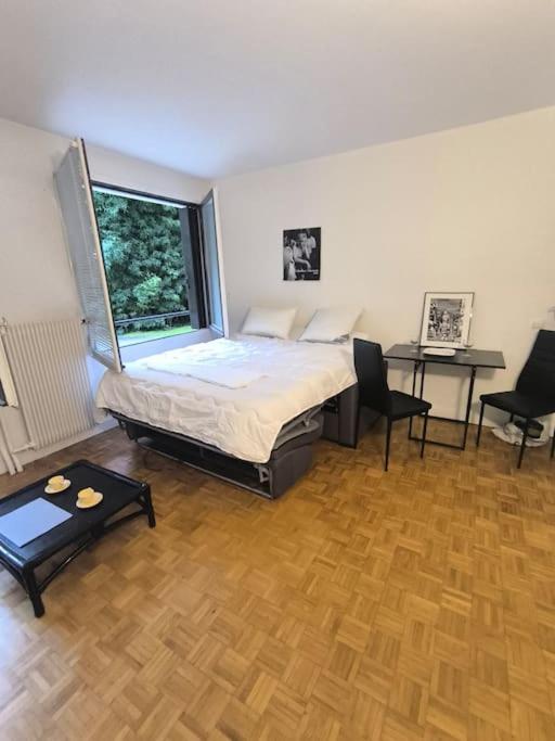 une chambre avec un lit et deux chaises et une fenêtre dans l'établissement Studio Neuilly sur Seine, à Neuilly-sur-Seine