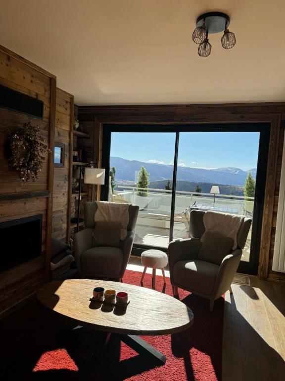 a living room with a table and chairs and a large window at Le Petit Chalet du Belvédère in Font Romeu Odeillo Via