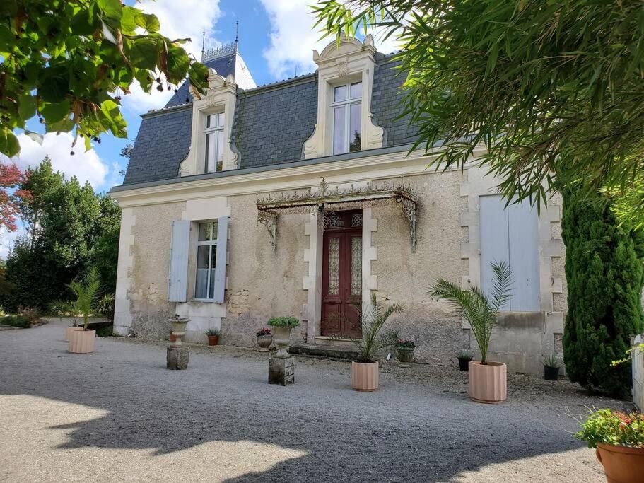 a white house with a red door and potted plants at La Grelauderie 7 in Saintes