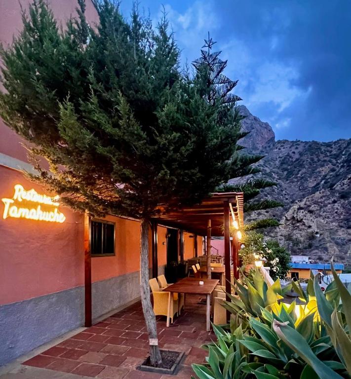 a tree sitting outside of a restaurant with a table at Tamahuche Hotel Rural in Vallehermoso