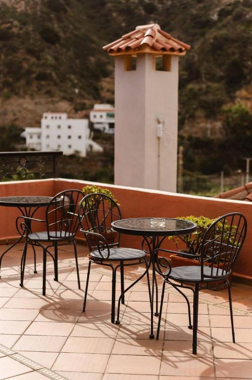 two tables and chairs on a balcony with a bird house at Tamahuche Hotel Rural in Vallehermoso