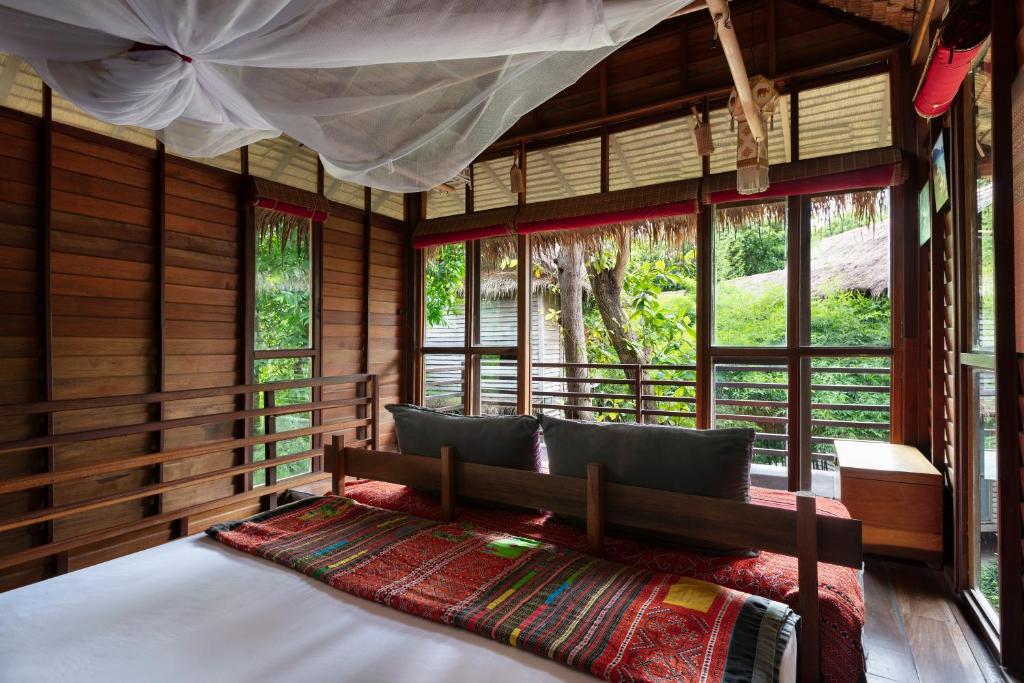 ein Schlafzimmer mit einem Bett in einem Zimmer mit Fenstern in der Unterkunft Castaway Resort Koh Lipe in Ko Lipe