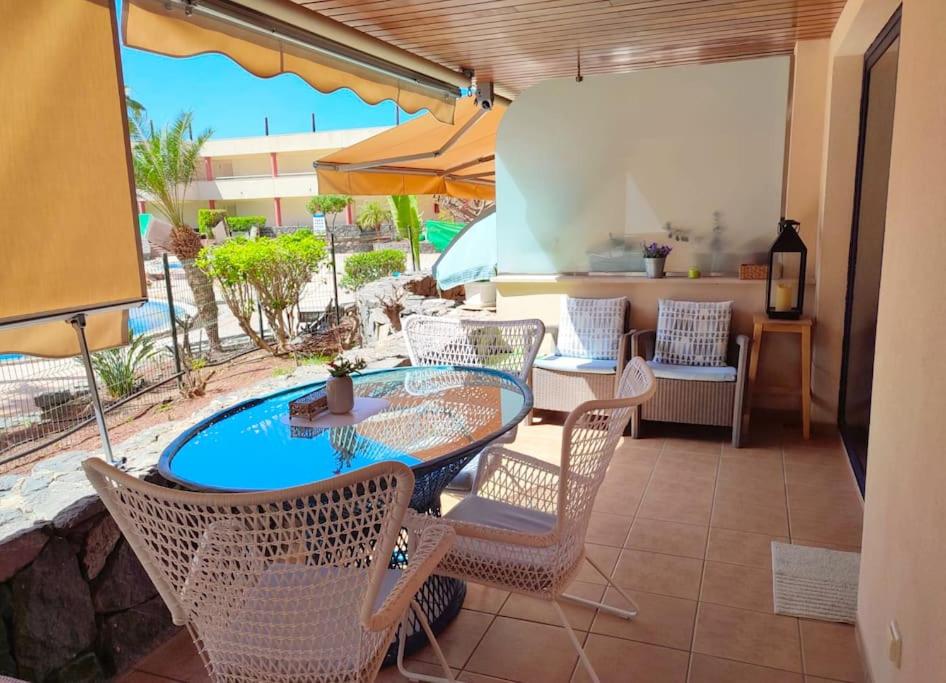 Un patio con mesa y sillas y una piscina. en Apartment Balcon, cosy one bed with AirCon and pool, en Puerto de Santiago